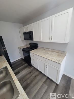 La Crosse apartment for rent - A kitchen with white cabinets and a black fridge.