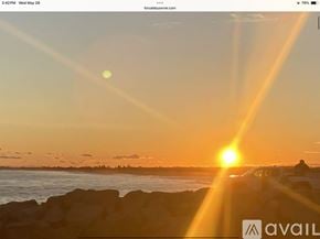 South Kingstown house for rent - A sunset scene with a bright sun and a person standing on the shore.