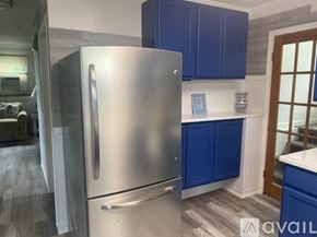 South Kingstown house for rent - A stainless steel refrigerator in a kitchen with blue cabinets.
