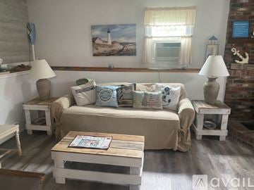 South Kingstown house for rent - A living room with a couch, two lamps, and a painting on the wall.
