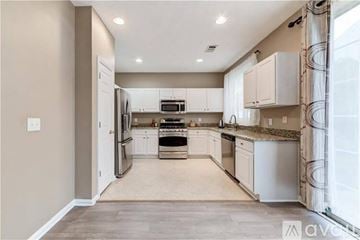 Alpharetta house for rent - A kitchen with white cabinets and appliances, and a beige wall.