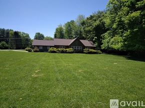 Hillsboro house for rent - A house with a brown roof is surrounded by a green lawn and trees.