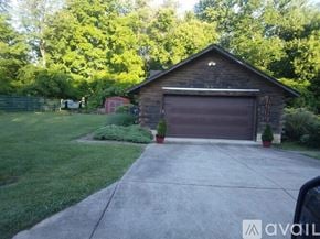Hillsboro house for rent - A wooden garage with a brown door is surrounded by greenery.