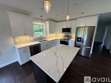 Hermantown house for rent - A kitchen with a white marble island and wooden floors.