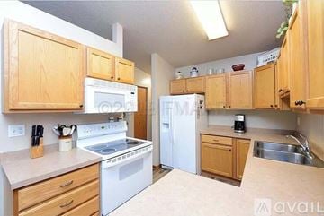 Fargo house for rent - A kitchen with wooden cabinets and white appliances.