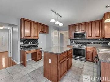 Fenton house for rent - A kitchen with wooden cabinets and a granite countertop.
