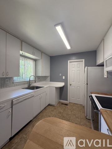 Village Of Clarkston house for rent - A kitchen with white cabinets and a wooden table.