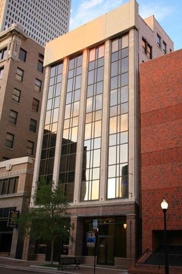 Tulsa apartment for rent - A tall building with a red brick wall and a glass window.