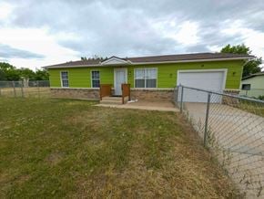 Walsenburg house for rent - A green house with a brown fence and a white garage door.