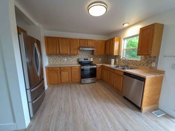 Walsenburg house for rent - A kitchen with wooden cabinets and a stainless steel refrigerator.