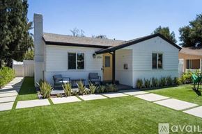 Los Angeles house for rent - A house with a white exterior and a brown roof has a patio with a table and chairs.