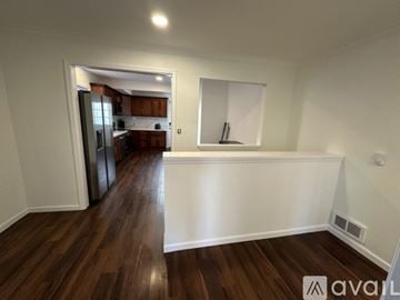 Tacoma townhouse for rent - A room with wooden floors and a kitchen area in the background.