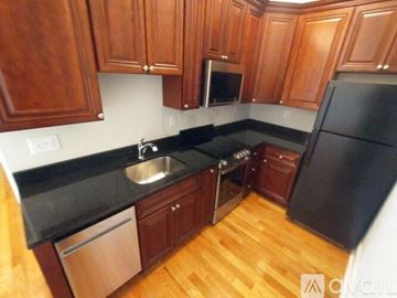 Watertown apartment for rent - A kitchen with wooden cabinets and black appliances.