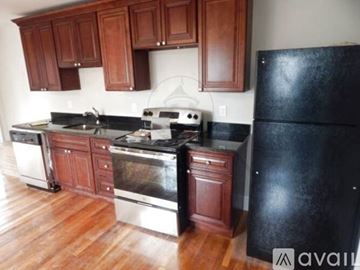 Somerville apartment for rent - A kitchen with wooden cabinets and a black refrigerator.