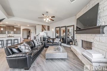 Crowley house for rent - A modern living room with a black leather couch and a fireplace.
