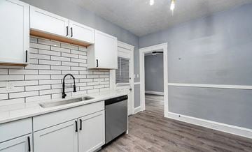 Cleveland apartment for rent - A kitchen with white cabinets and a black faucet.
