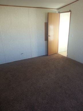 Billings house for rent - A room with a brown carpet and a wooden door.