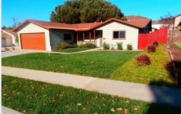 Camarillo house for rent - A house with a red garage door is surrounded by a green lawn.