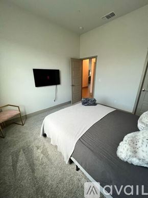 Merced house for rent - A bedroom with a bed, a chair, and a TV mounted on the wall.