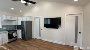 Santa Ana apartment for rent - A modern kitchen with a stainless steel refrigerator and a flat screen TV mounted on the wall.