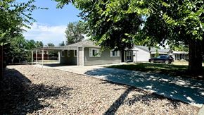 Aurora apartment for rent - A house with a gravel driveway and trees in front.