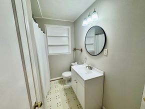 Columbia house for rent - A white bathroom with a toilet, sink, and mirror.