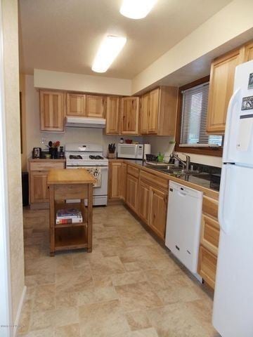Kenai apartment for rent - A kitchen with wooden cabinets and a white refrigerator.