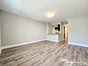 Chicago condo for rent - A long hallway with wood flooring and white walls.