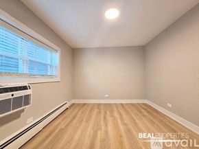 Chicago condo for rent - A spacious room with wooden flooring and a large window.