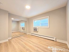 Chicago condo for rent - A spacious room with a window, a mirror, and a wall-mounted air conditioner unit.
