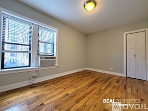 Chicago condo for rent - A white bedroom with a window and a wooden floor.