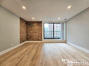 Chicago condo for rent - A living room with a white couch, a coffee table, and a brick wall.
