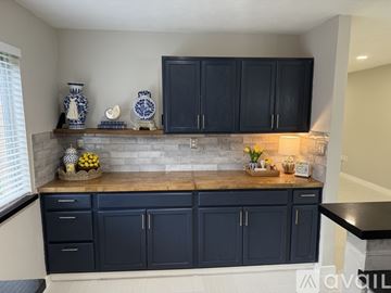 Houston house for rent - A kitchen with dark blue cabinets and a stone backsplash.