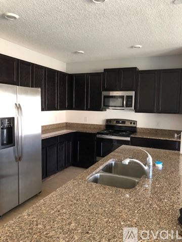 Kissimmee house for rent - A kitchen with black cabinets and granite countertops.