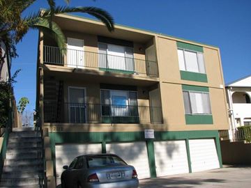 San Diego apartment for rent - A car is parked in front of a building with a balcony.