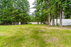 Langley apartment for rent - A grassy field with trees and a white building in the background.