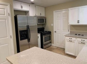 Bay City house for rent - A kitchen with white cabinets and a granite countertop.