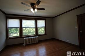 Chicago apartment for rent - A room with a ceiling fan and a window with a view of trees.