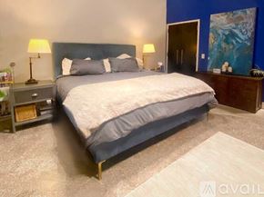 Richmond apartment for rent - A bedroom with a large bed and a nightstand with a lamp.