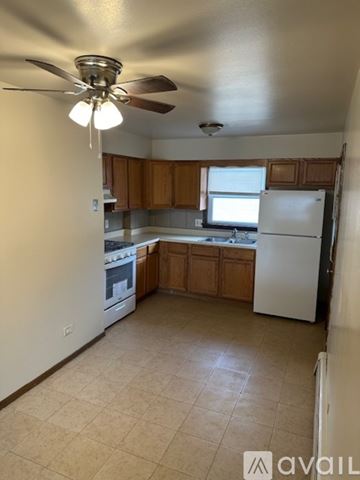 Dolton apartment for rent - A kitchen with a white refrigerator and wooden cabinets.