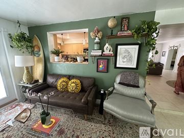Naples house for rent - A living room with a brown couch, a grey chair, and a rug with a red book on it.