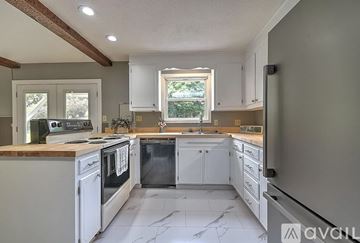 Bristol apartment for rent - A kitchen with white cabinets and appliances, a marble floor, and a window with a view of trees.