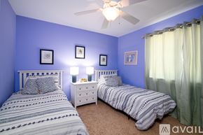 Folly Beach condo for rent - A bedroom with two beds, one with a white headboard and the other with a striped comforter.