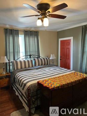 Indianapolis townhouse for rent - A bedroom with a bed, a ceiling fan, and a red door.