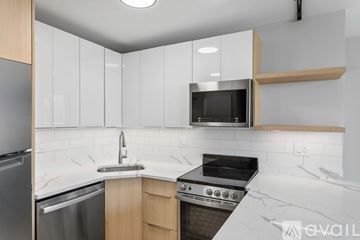 Chicago apartment for rent - A kitchen with a stainless steel refrigerator, a microwave above the stove, and a marble countertop.