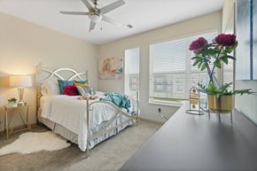 Greenfield apartment for rent - A bedroom with a bed, a fan, and a vase of flowers.