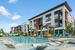 Greenfield apartment for rent - A large swimming pool in front of a multi-story apartment building.