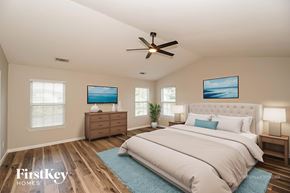 Midland house for rent - A bedroom with a large bed, a ceiling fan, and two picture frames on the wall.