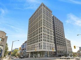 Toronto apartment for rent - A large, modern building with many windows is situated on a street corner.