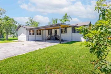 Houma apartment for rent - A white house with a brown roof and a green lawn in front.